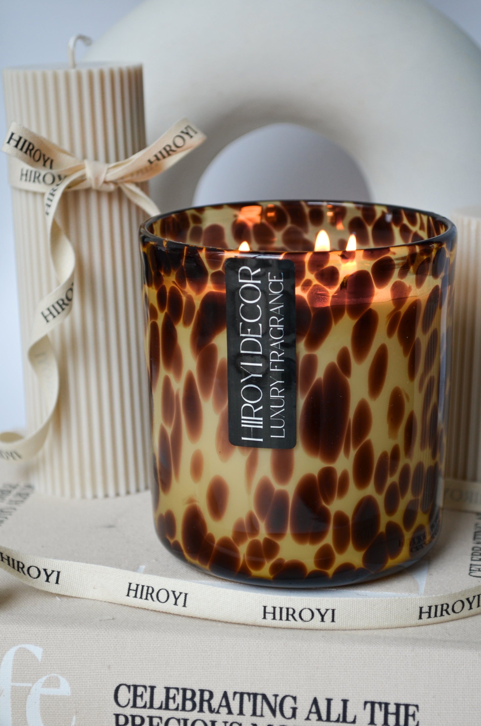 Candle with leopard print design on a surface with 'HIROYI' branding.